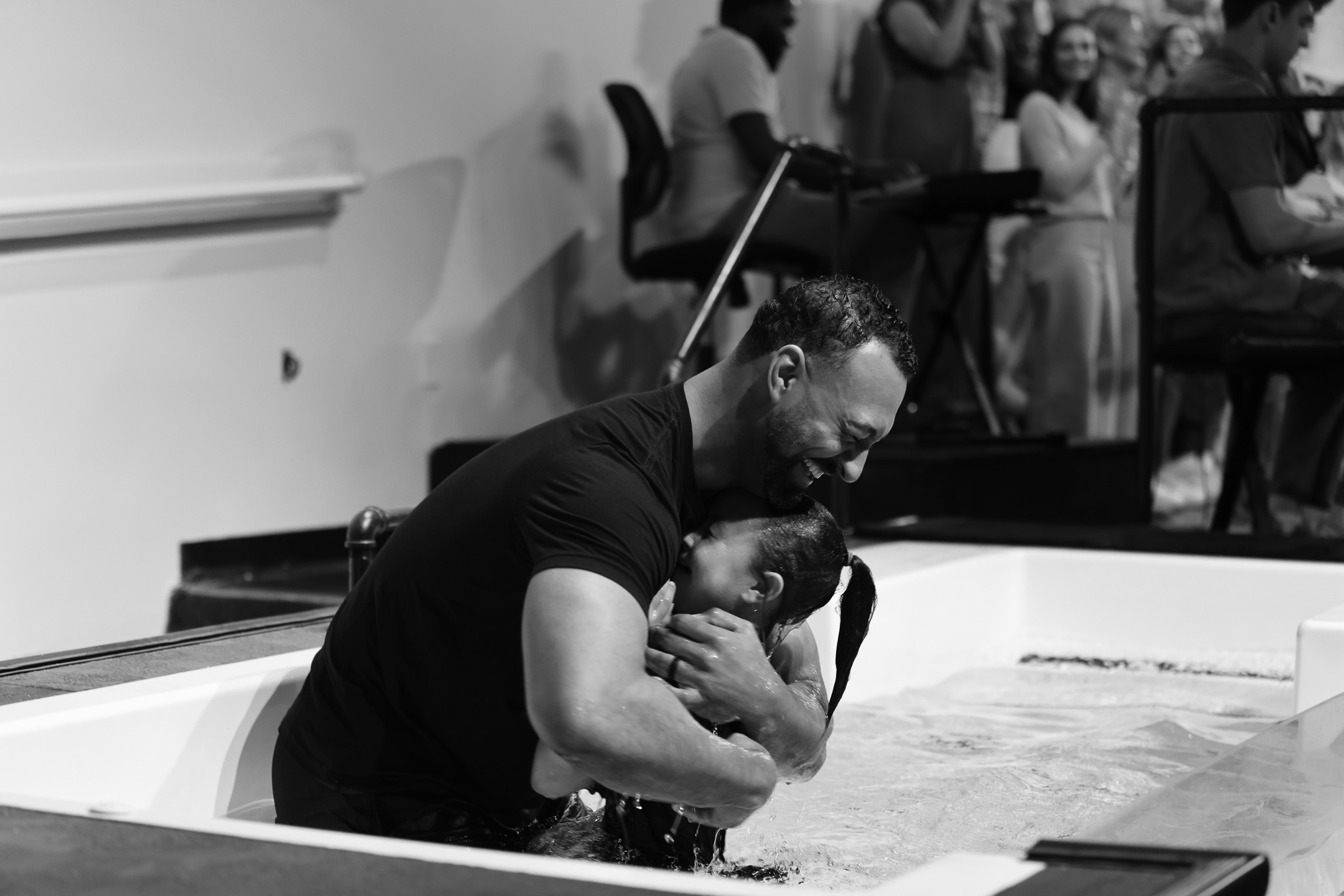 A pastor embraces a person during baptism in the church baptism pool